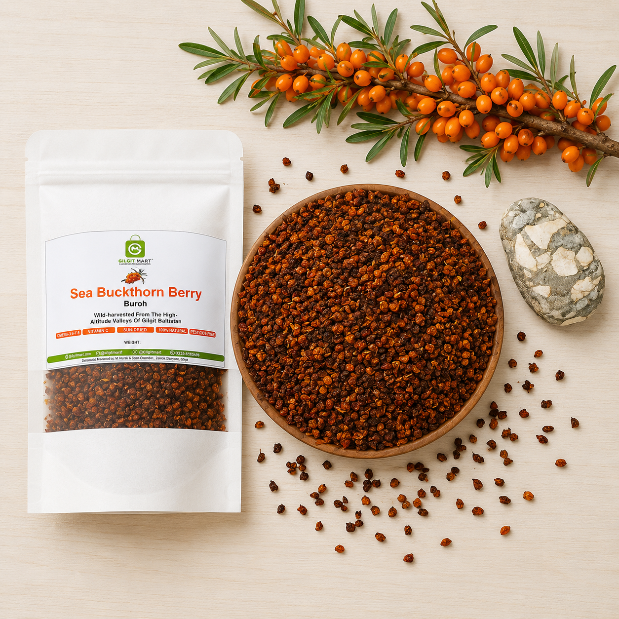 A white stand-up pouch of Sea Buckthorn Berry Blends next to a wooden bowl filled with dried reddish-brown Seabuckthorn berries, arranged on a light wood surface with scattered berries, a branch of orange berries, and a small stone.
